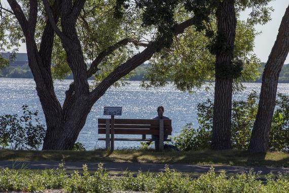 Student sitting on a bench in front of Lake Bemidji
